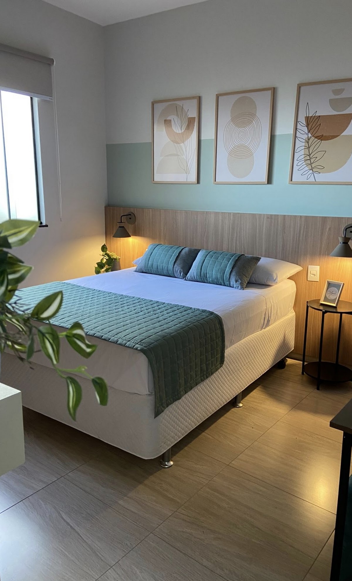 Quarto do estúdio com cama queen, quadros decorativos e iluminação suave